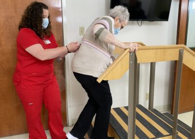 patient walking over an arch with steps assisted by rehab staff